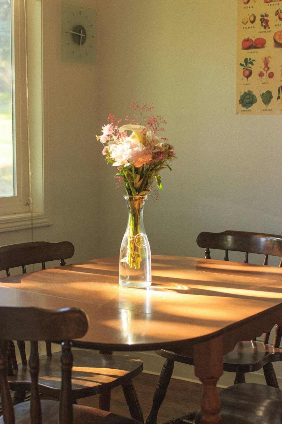 Holztisch mit rosa und weißen Blumen in einer Vase.